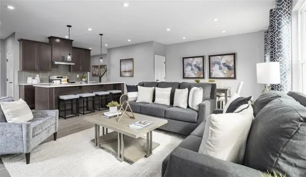 a living room with furniture kitchen view and a wooden floor
