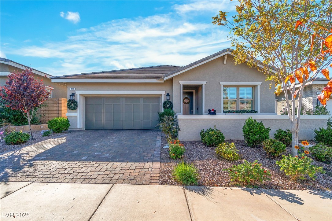 Ranch-style home with decorative driveway, stucco siding, an attached garage, and a tiled roof