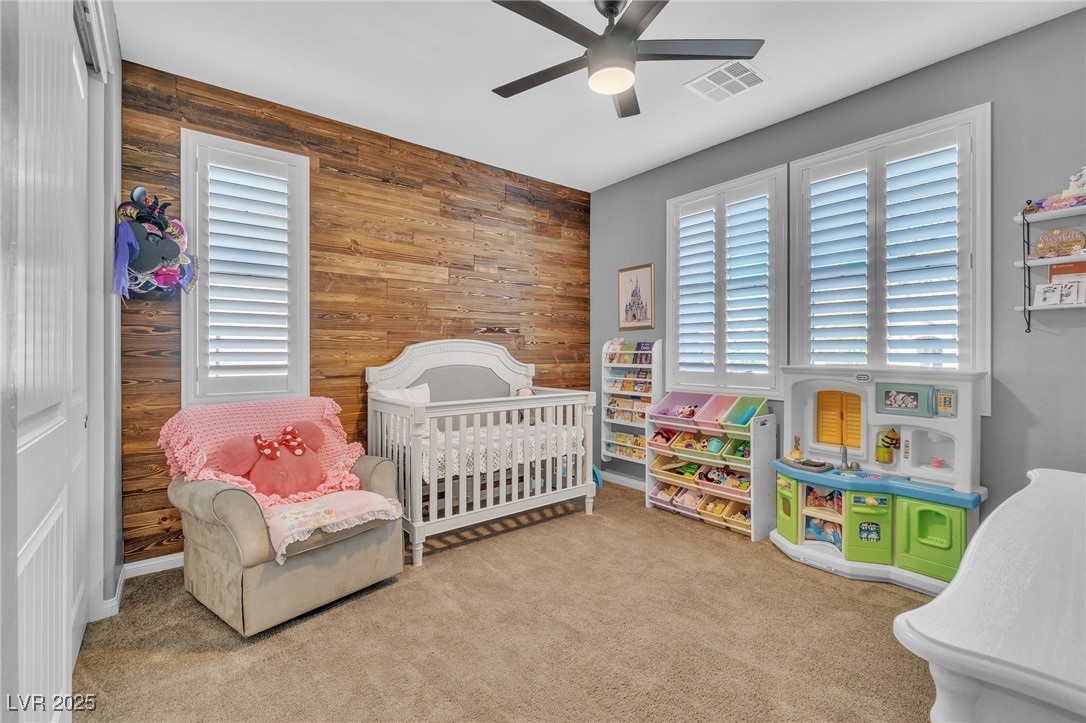 119 Mosso Niente Place Henderson, NV 89011 - Photo 19 of 36 Bedroom featuring wooden walls, a crib, carpet floors, and a ceiling fan