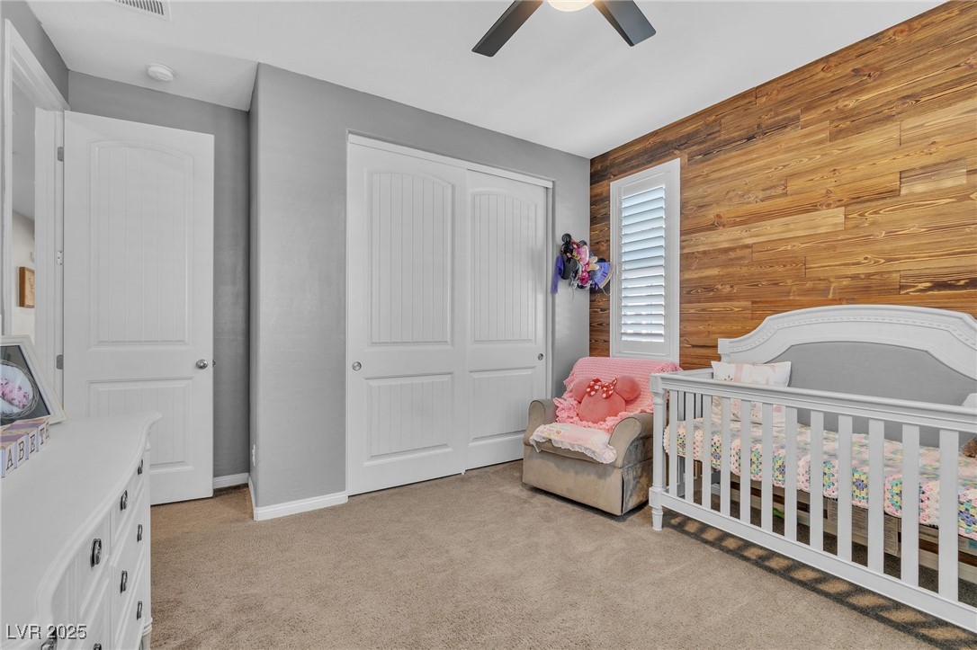 119 Mosso Niente Place Henderson, NV 89011 - Photo 20 of 36 Bedroom with wooden walls, a crib, light carpet, a closet, and ceiling fan
