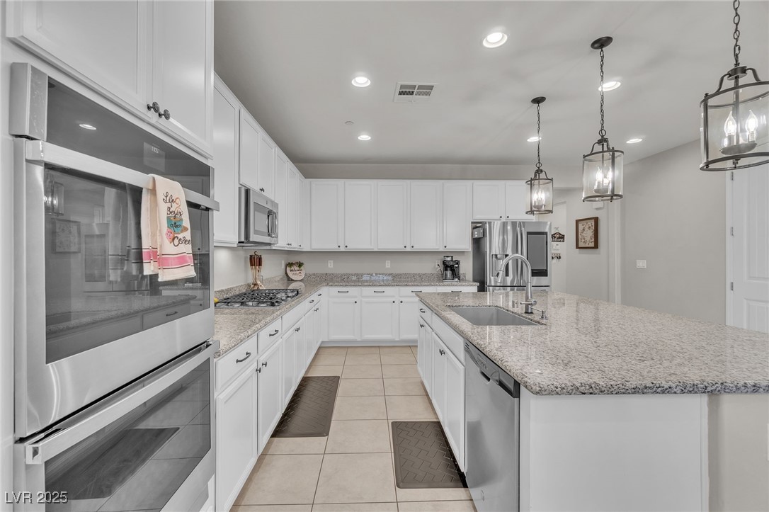 119 Mosso Niente Place Henderson, NV 89011 - Photo 5 of 36 Kitchen featuring appliances with stainless steel finishes, recessed lighting, white cabinetry, pendant lighting, and light stone countertops