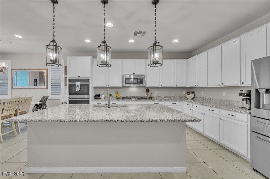 119 Mosso Niente Place Henderson, NV 89011 - Photo 6 of 36 Kitchen featuring white cabinets, decorative light fixtures, stainless steel appliances, recessed lighting, and a kitchen island with sink