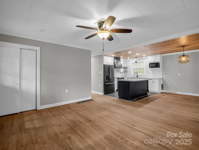 a view of kitchen and empty room with wooden floor