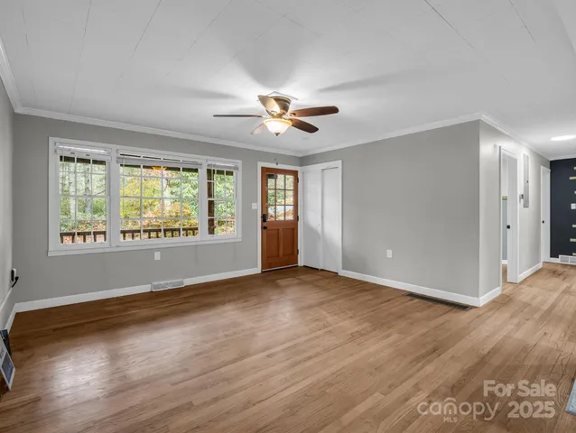 a view of an empty room with window and wooden floor