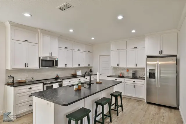 a kitchen with stainless steel appliances granite countertop a sink a stove a refrigerator and cabinets