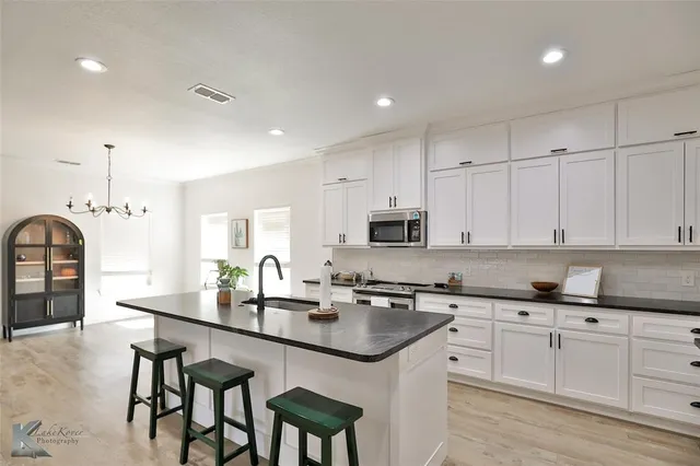 a kitchen with granite countertop a sink white cabinets and stainless steel appliances