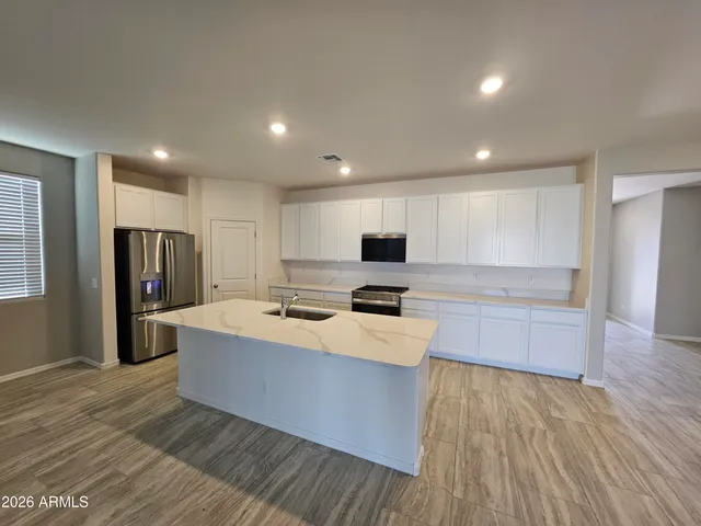 a large kitchen with stainless steel appliances a large counter top a sink a refrigerator and a refrigerator