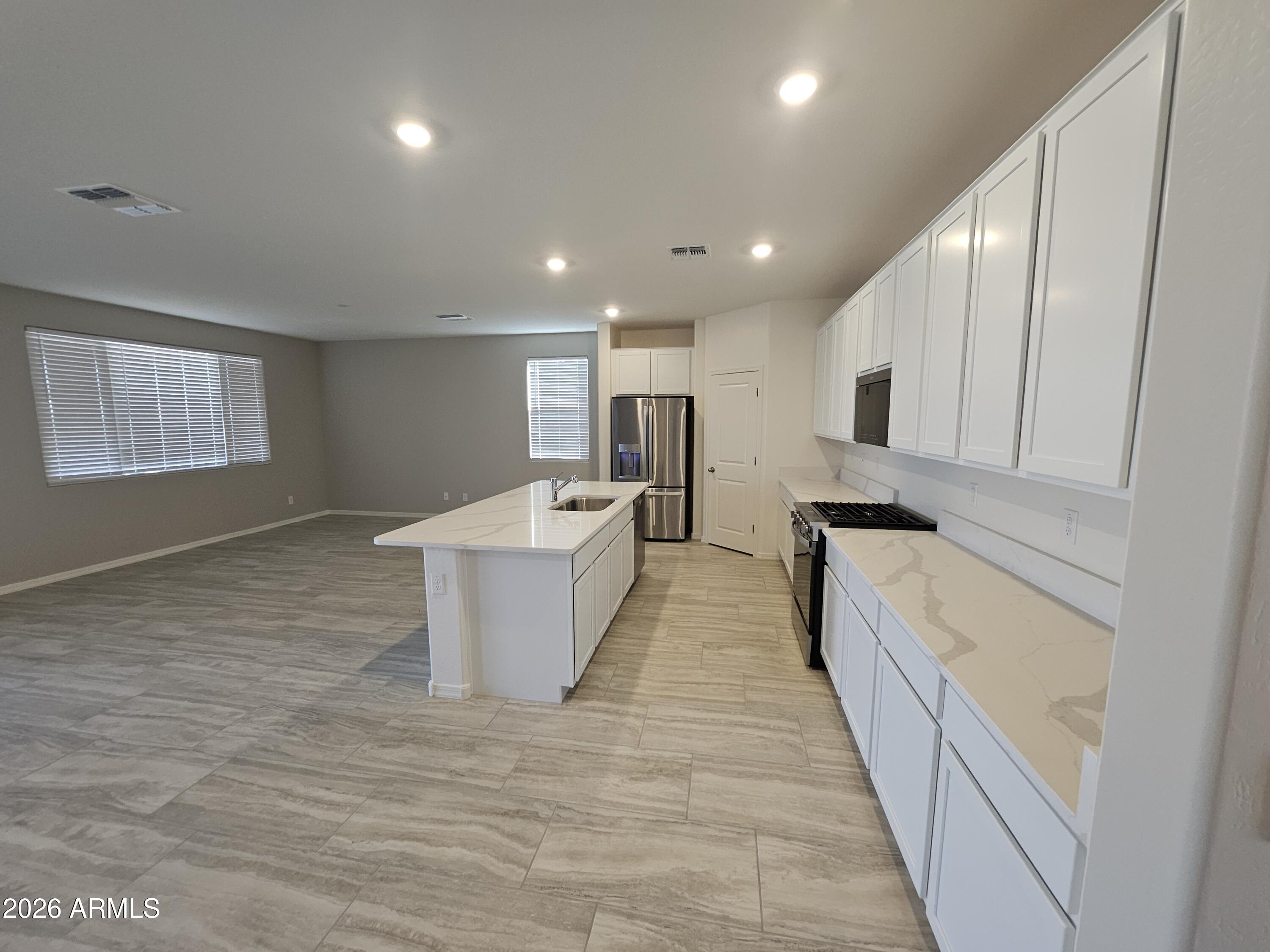 3010 East Augusta Avenue Gilbert, AZ 85298 - Photo 5 of 33 a large kitchen with kitchen island a sink a center island stainless steel appliances and a window