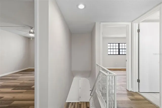a view of empty room with wooden floor and fan