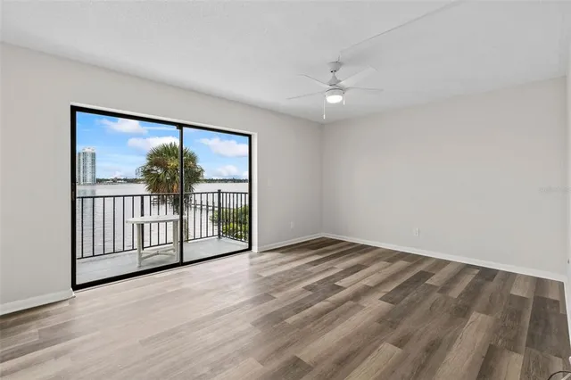 a view of empty room with wooden floor and fan