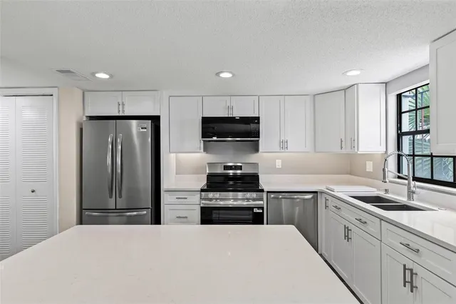 a kitchen with stainless steel appliances kitchen island granite countertop a refrigerator and a stove top oven