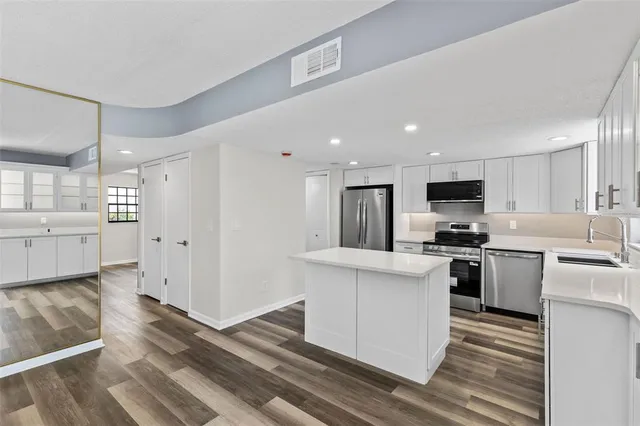 a kitchen with stainless steel appliances granite countertop white cabinets a sink a stove a refrigerator and white cabinets