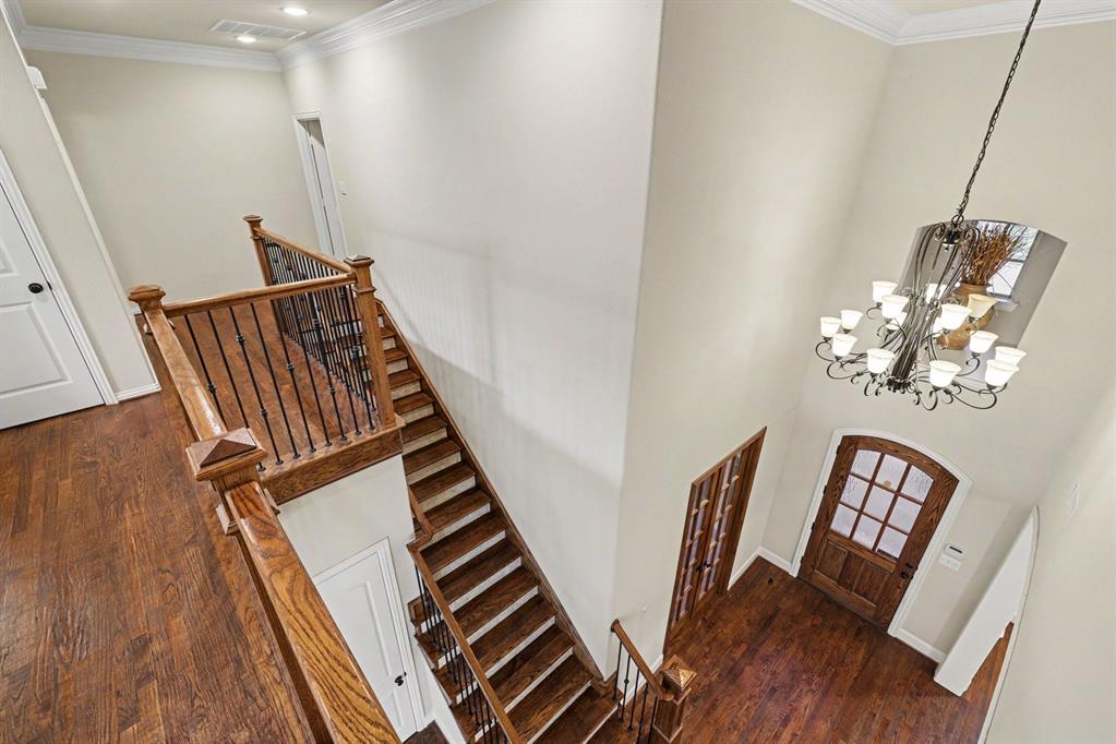 408 Blue Ridge Court Allen, TX 75013 - Photo 10 of 31 Two-story entryway with a wood-finish staircase featuring wrought iron balusters, a wood-finish front door with glass panels, and a multi-arm chandelier