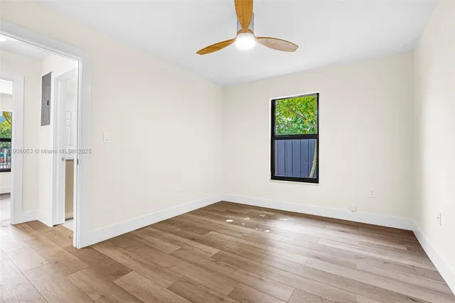 an empty room with wooden floor chandelier fan and windows