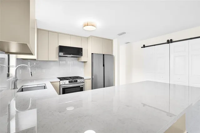 a kitchen with granite countertop a sink a stove and refrigerator