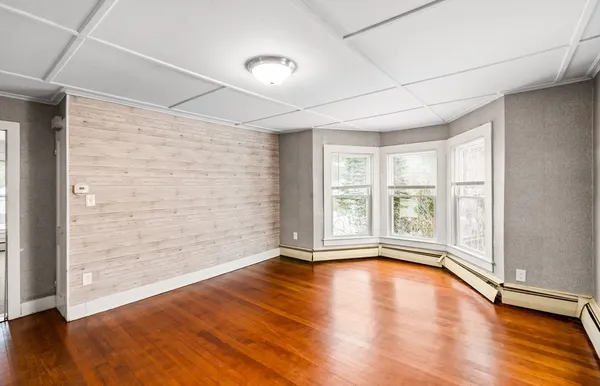 a view of an empty room with a window and wooden floor