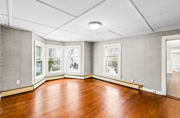 a view of an empty room with wooden floor and a window