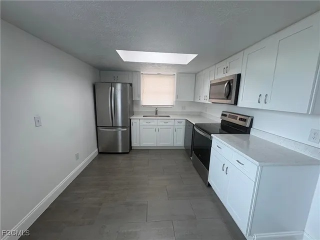 a kitchen with granite countertop stainless steel appliances and white cabinets