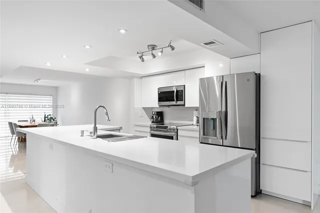 a large white kitchen with a sink stainless steel appliances and cabinets