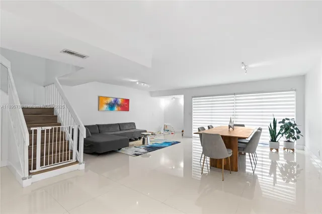 a living room with furniture and a dining table with potted plants