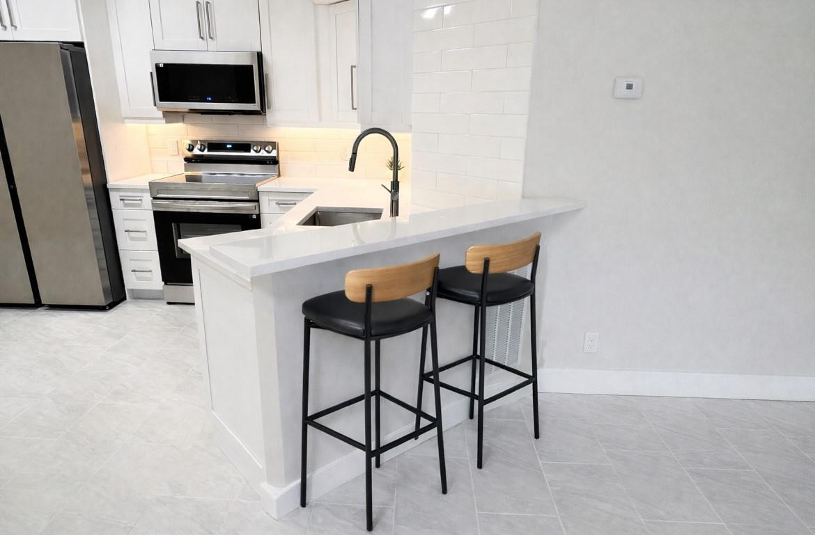 9055 Wiles Road, Unit 208 Coral Springs, FL 33067 - Photo 3 of 35 a kitchen with stainless steel appliances a stove a sink and a refrigerator
