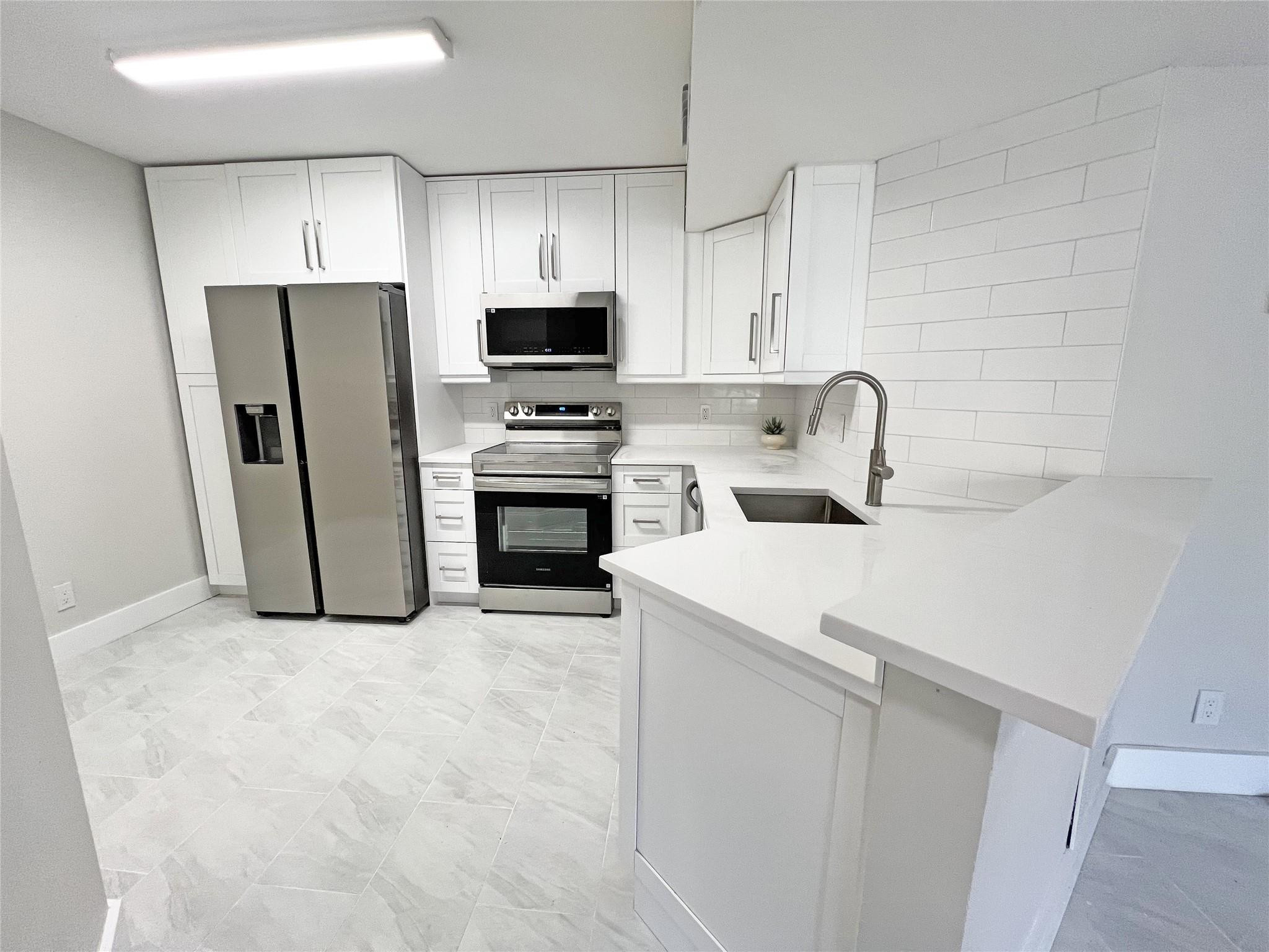 9055 Wiles Road, Unit 208 Coral Springs, FL 33067 - Photo 5 of 35 a kitchen with stainless steel appliances a refrigerator stove microwave and sink