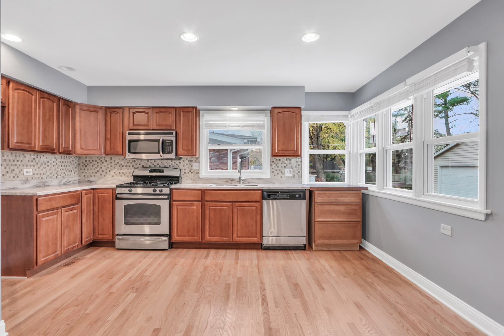 1186 Highland Road Mundelein, IL 60060 - Photo 8 of 28 a large kitchen with stainless steel appliances granite countertop a stove a sink dishwasher and a microwave oven with wooden floor