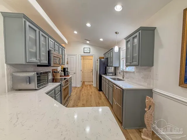 a large kitchen with stainless steel appliances granite countertop a lot of counter space and a sink