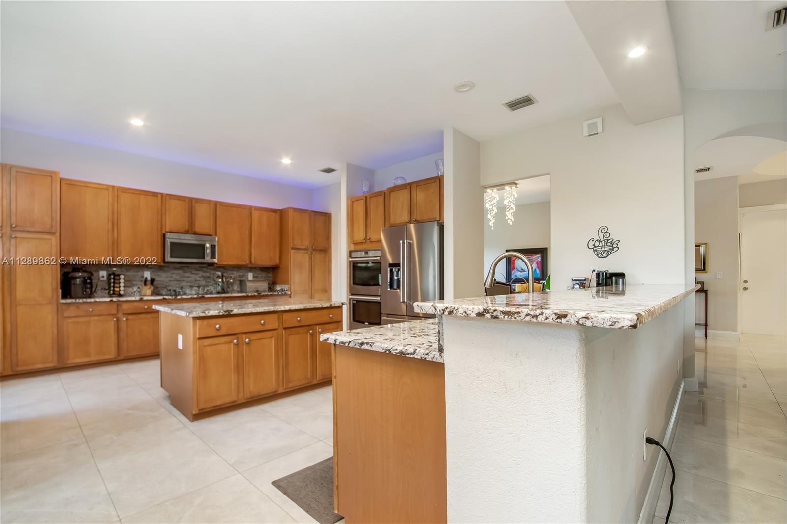 7783 Southwest 188th Street Cutler Bay, FL 33157 - Photo 25 of 70 a kitchen with stainless steel appliances kitchen island granite countertop a sink and cabinets