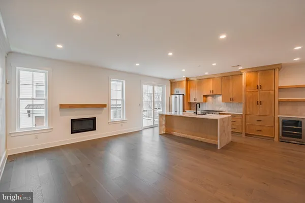 an empty room with kitchen view and a fireplace