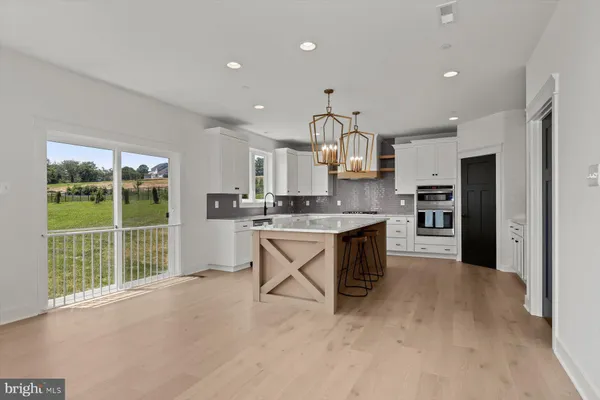 a large kitchen with kitchen island a large counter top stainless steel appliances and cabinets