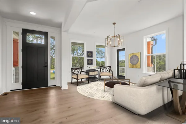 a living room with couches a table and chairs with wooden floor
