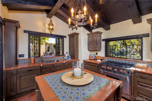 a kitchen with a stove a sink dishwasher and a dining table with garden view