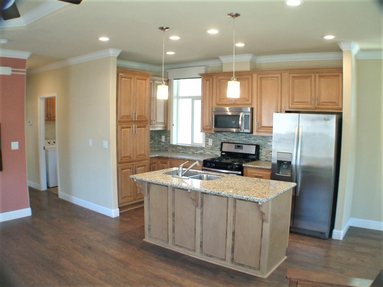 a kitchen with kitchen island granite countertop a sink a center island stainless steel appliances and a window