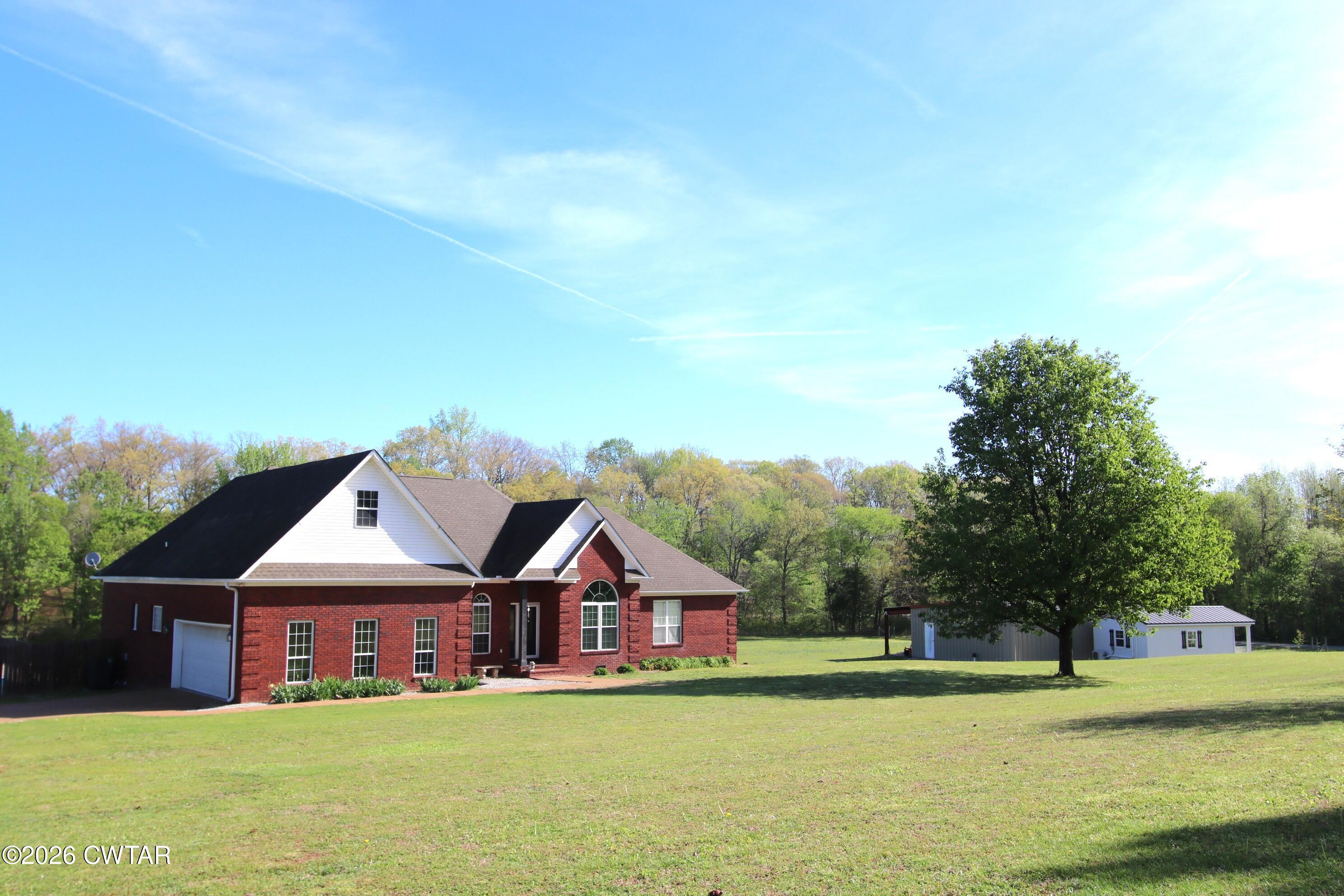 a view of a house next to a big yard with large trees