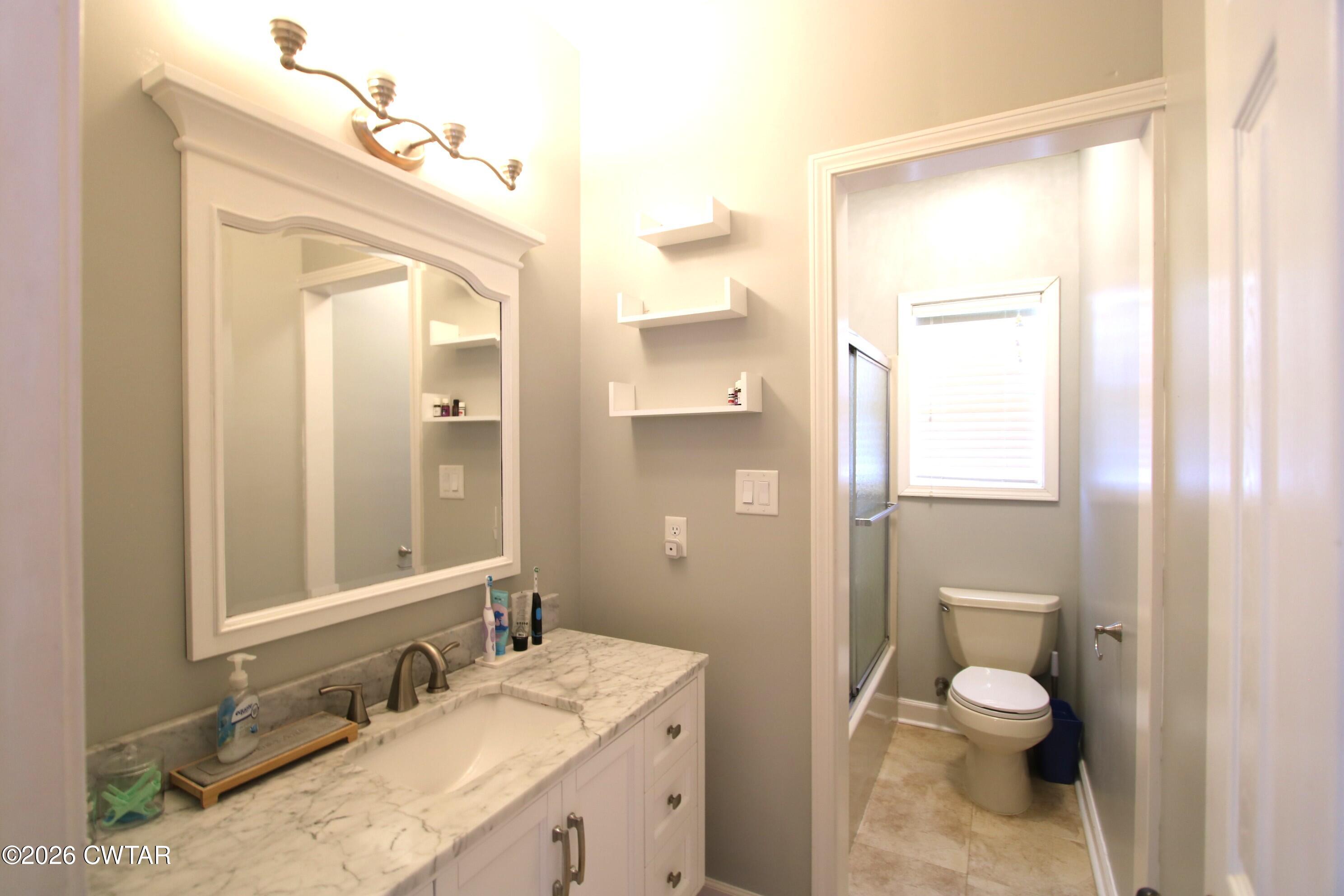 98 Browning Road Milan, TN 38358 - Photo 37 of 59 a bathroom with a granite countertop toilet a sink and a mirror