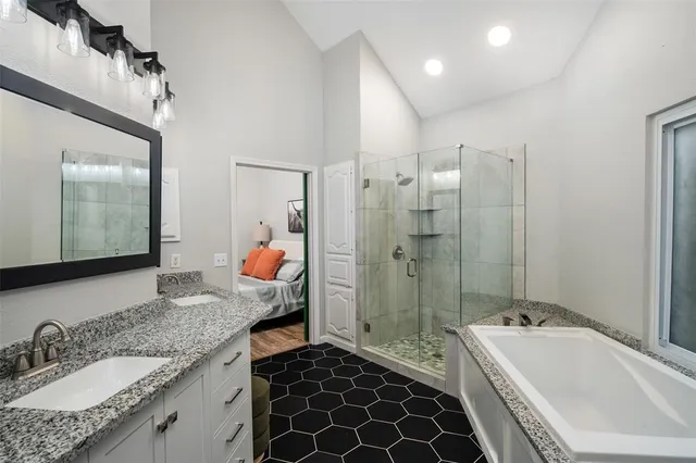 a bathroom with a granite countertop tub sink shower and mirror