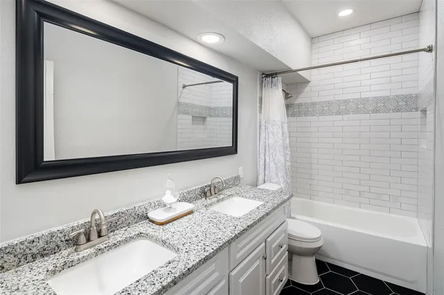 a bathroom with a granite countertop sink mirror toilet and bathtub