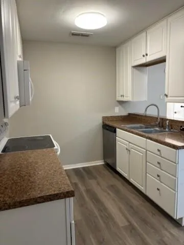 a kitchen with granite countertop white cabinets and a sink
