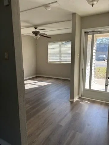a view of an empty room with wooden floor and a window