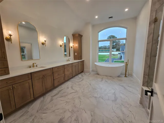a spacious bathroom with a granite countertop sink mirror and bathtub
