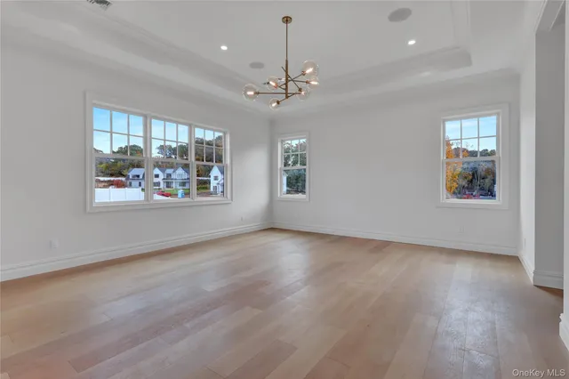 a view of an empty room with window and wooden floor