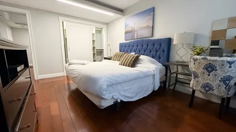 a view of a hallway with wooden floor and a bathroom