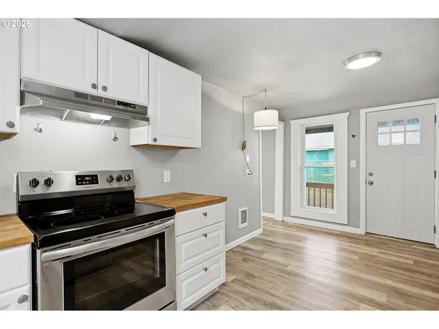 a kitchen with stainless steel appliances granite countertop a stove a sink and white cabinets