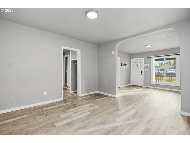 a view of an empty room with wooden floor and window