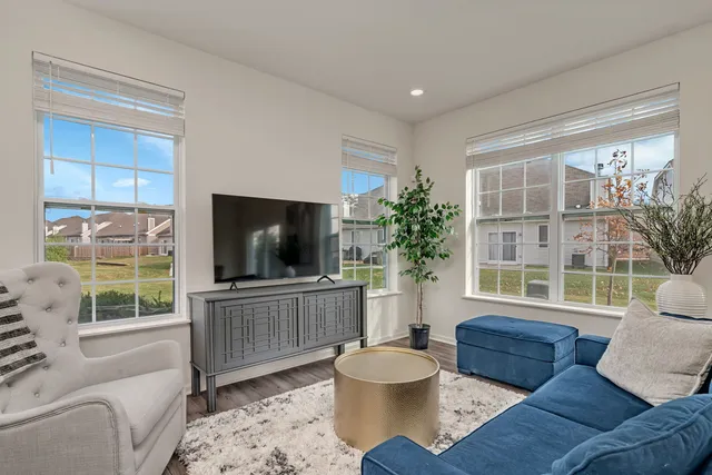 a living room with furniture a flat screen tv and a large window