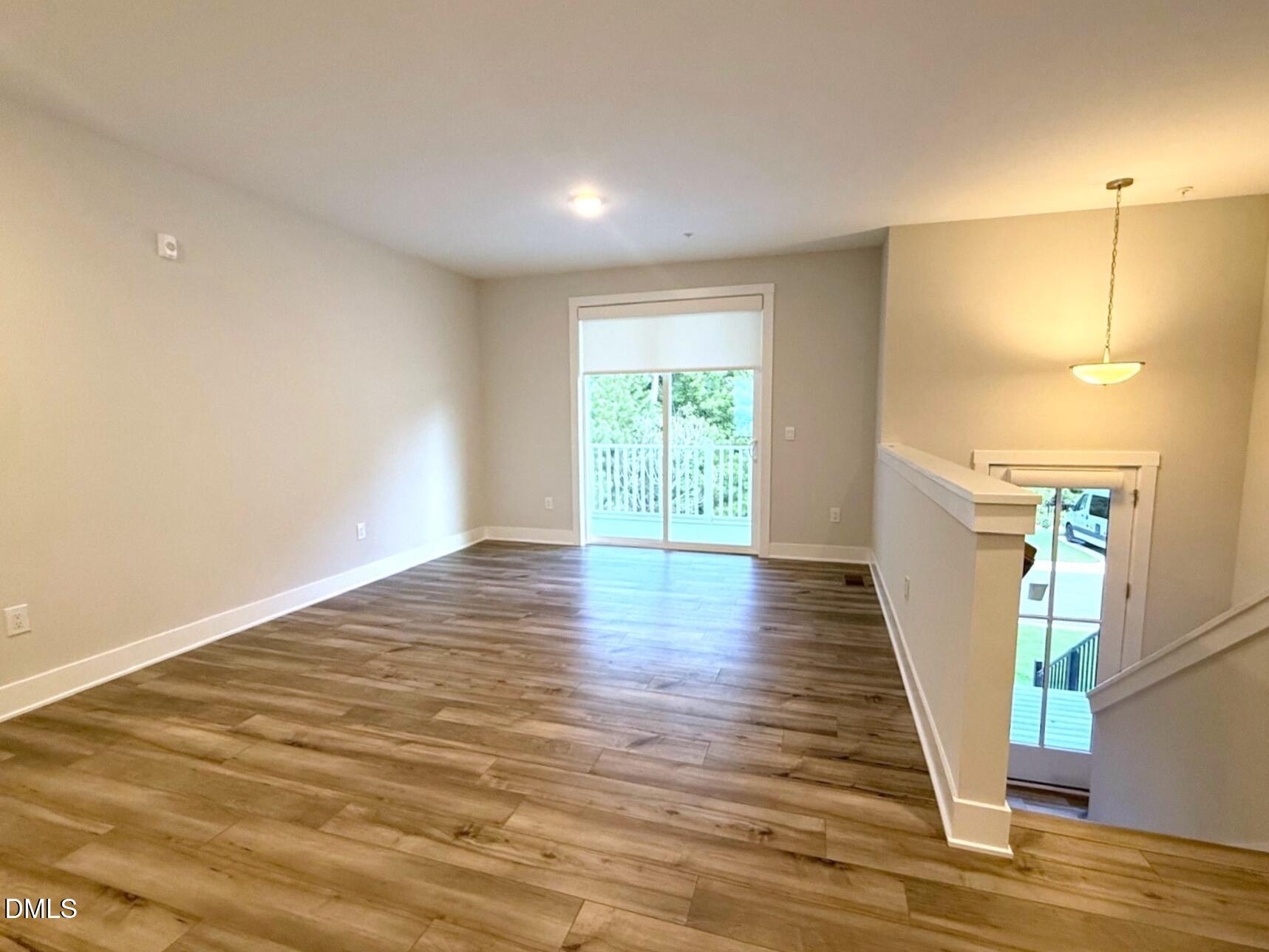 11549 Helmond Way, Unit 107 Raleigh, NC 27617 - Photo 5 of 33 a view of an empty room with wooden floor and a window