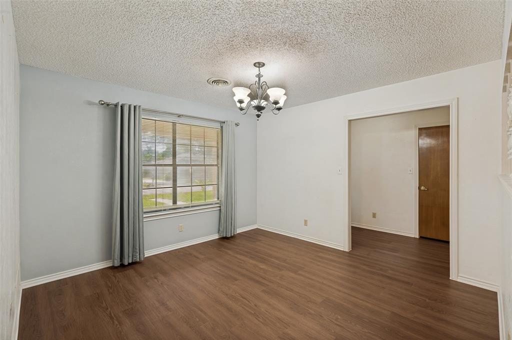 508 South Pedigo Street Pilot Point, TX 76258 - Photo 6 of 26 Spacious dining room featuring wood-finish flooring, light gray walls, and a window with gray drapes