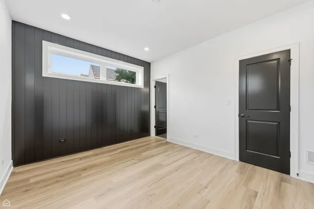 a view of an empty room with wooden floor and closet