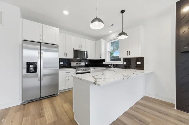 a kitchen with stainless steel appliances granite countertop a refrigerator a stove a sink and white cabinets